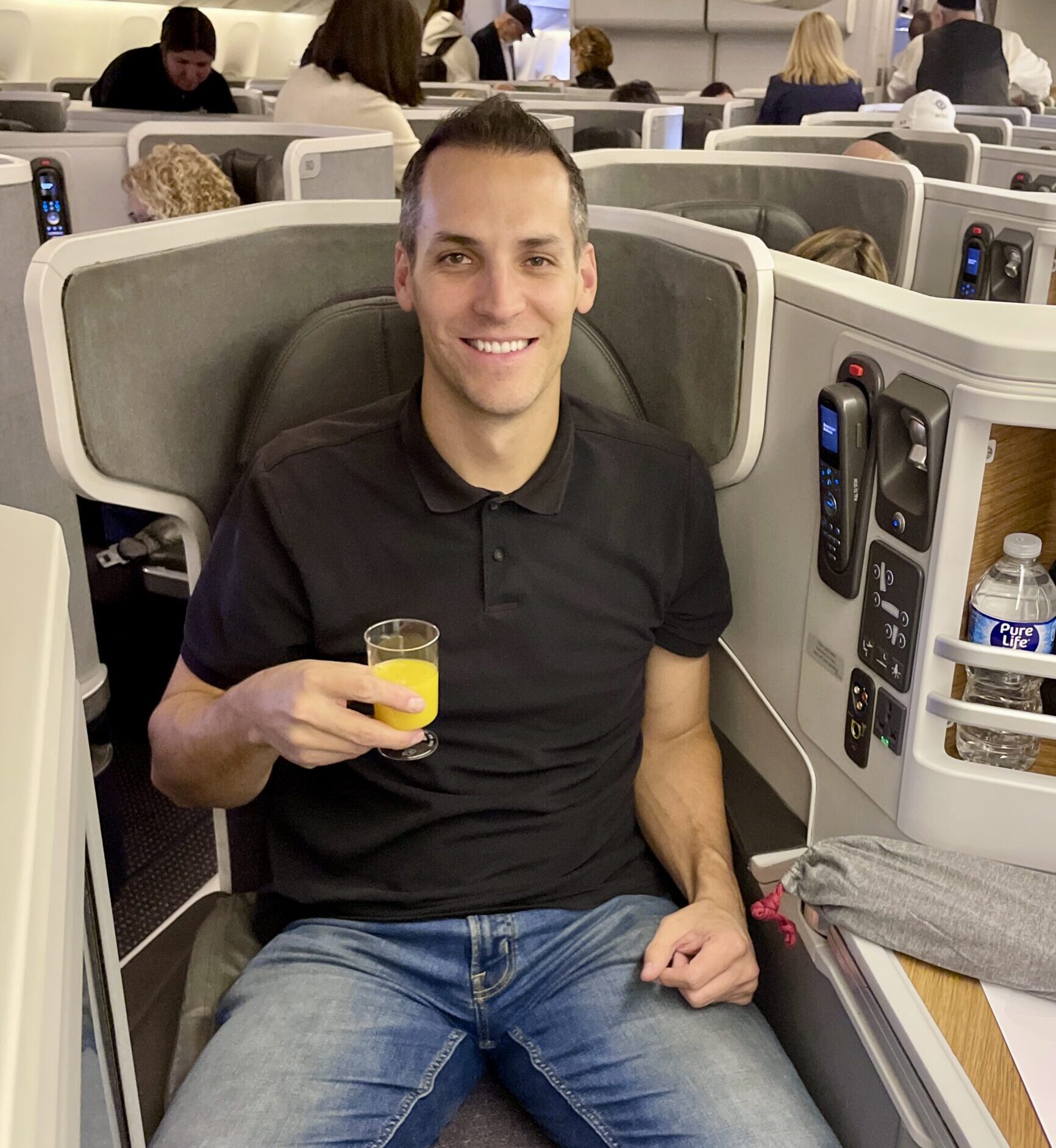 man in business class airplane seat with drink