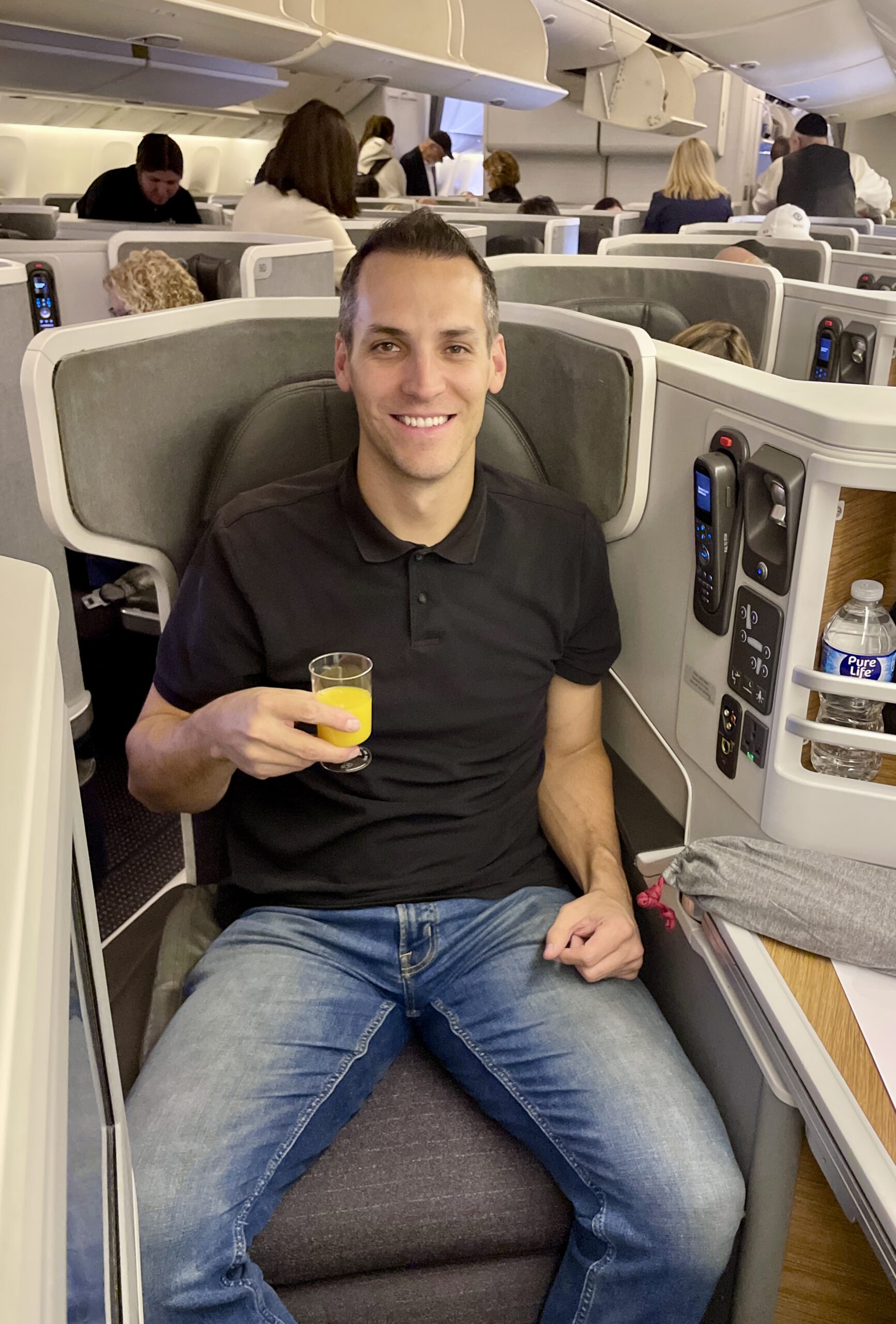 man in business class airplane seat with drink